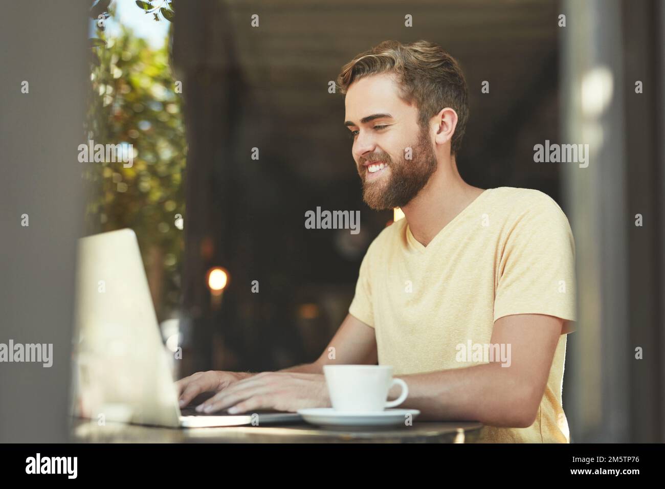 Coffee gets his thoughts flowing. a young man using a laptop in a cafe. Stock Photo