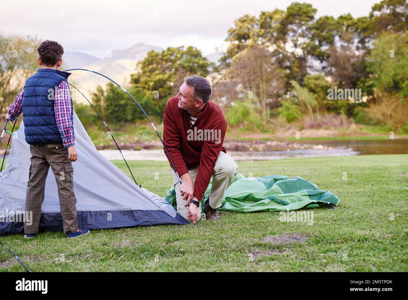 This tent is coming together now. a father and son setting up a tent
