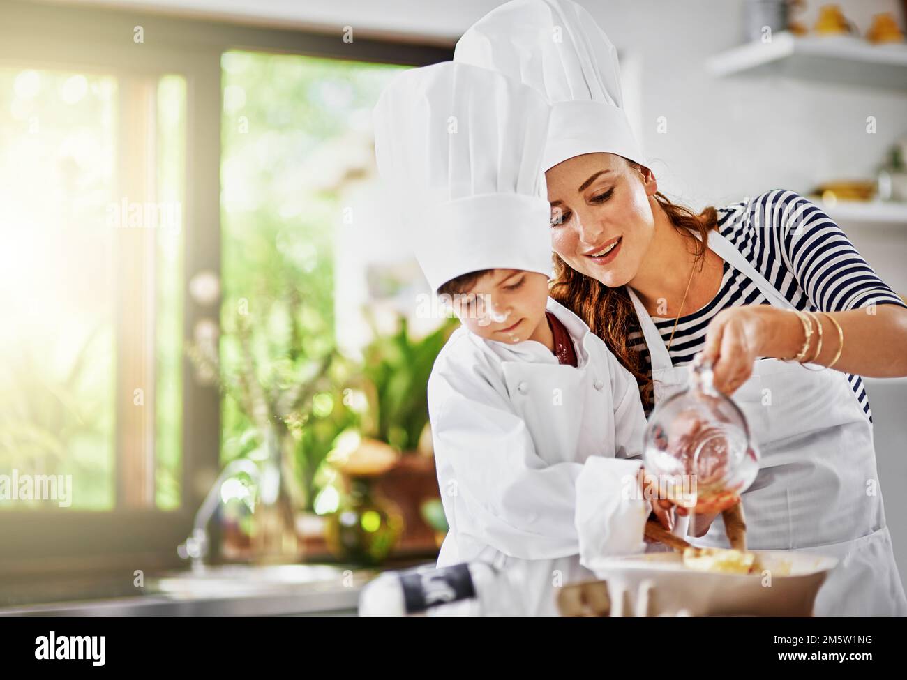 This baking class was a good idea for some bonding. a mother and her son baking in the kitchen. Stock Photo