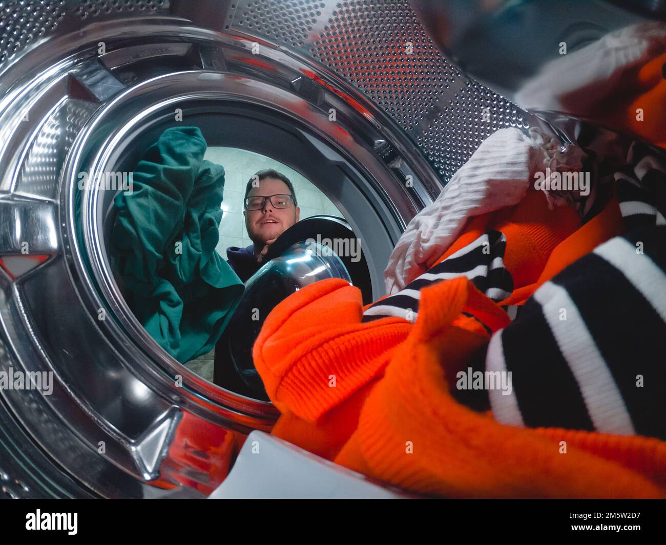 Man puts dirty clothes in washing machine Stock Photo - Alamy