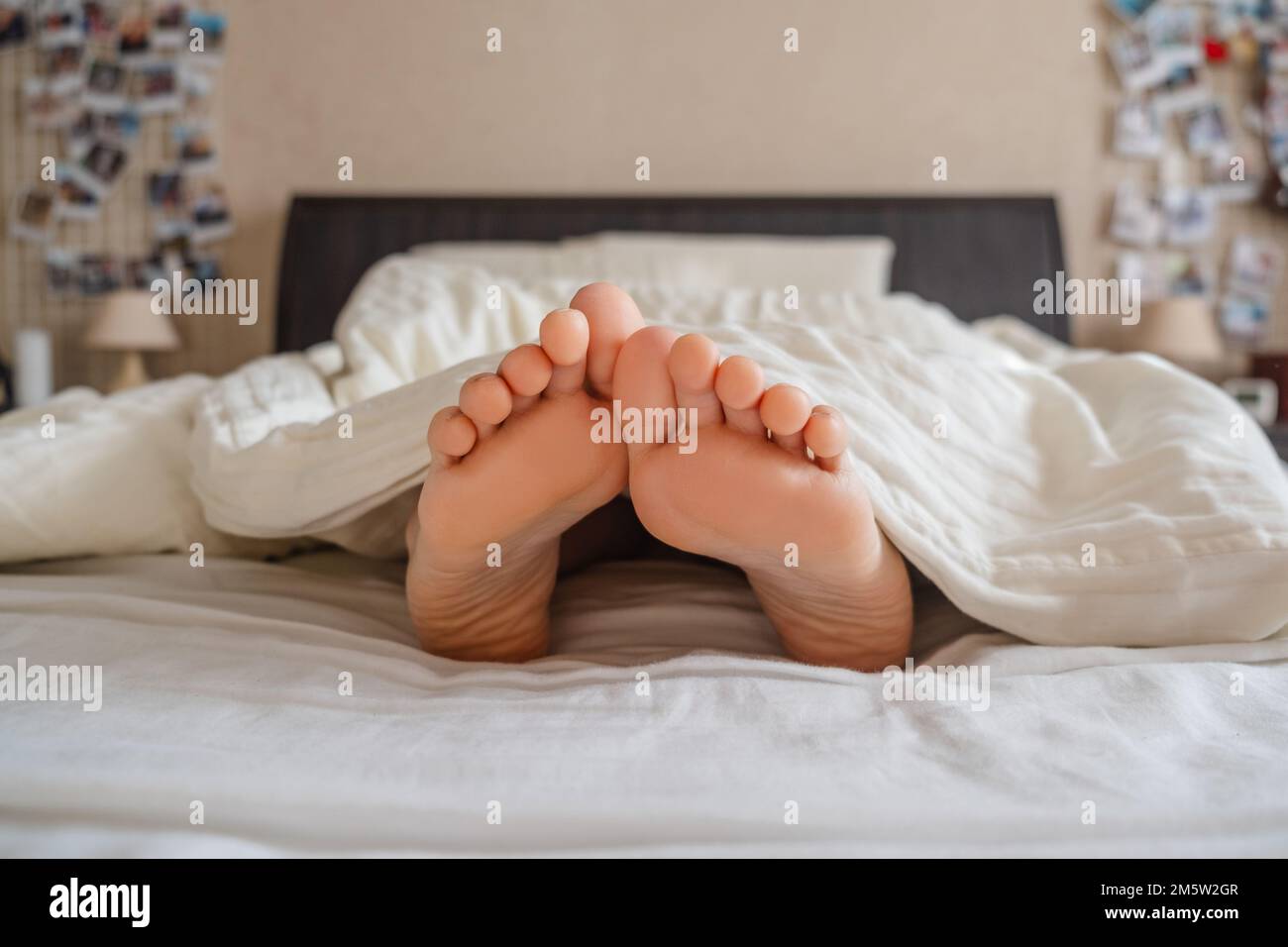 the woman's feet stick out from under the blankets Stock Photo Alamy