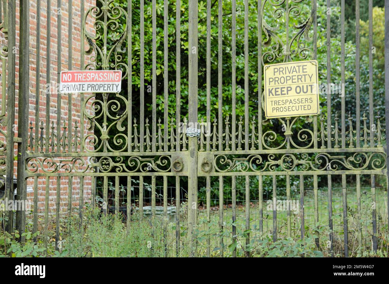 View from the street of some historic gates.  Chained closed with private property and no trespassing warning signs.  Aldermaston Court, Berkshire. Stock Photo