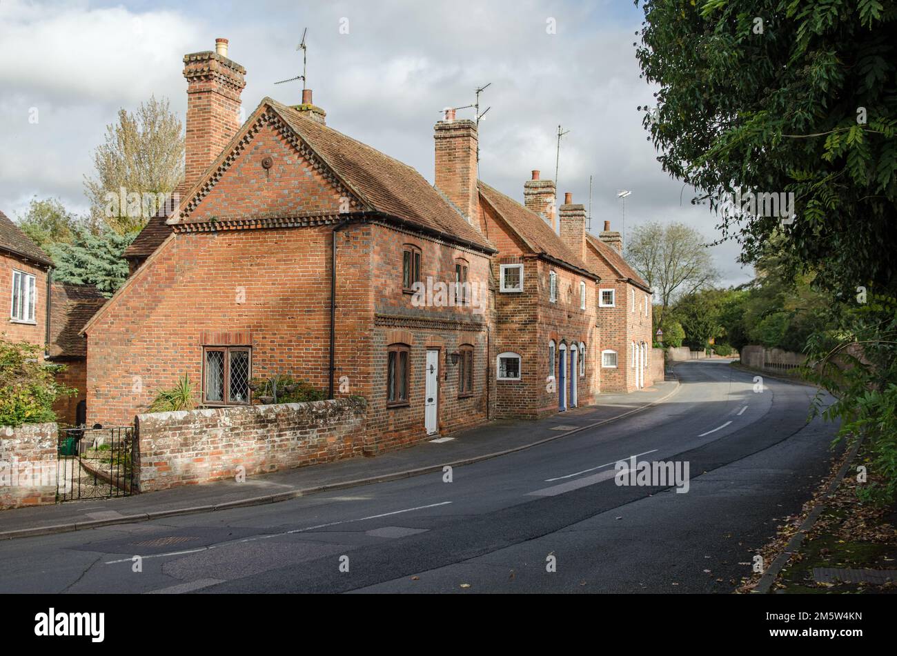 View along The Street in the middle of the village of Aldermaston with traditional, brick-built cottages on one side.  Sunny Autumn day in Berkshire. Stock Photo