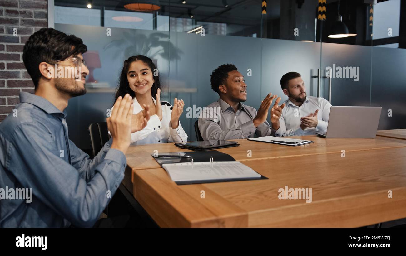 Happy multiethnic employees in office listen training diverse business people multinational team in boardroom applaud thank for seminar lecture clap Stock Photo