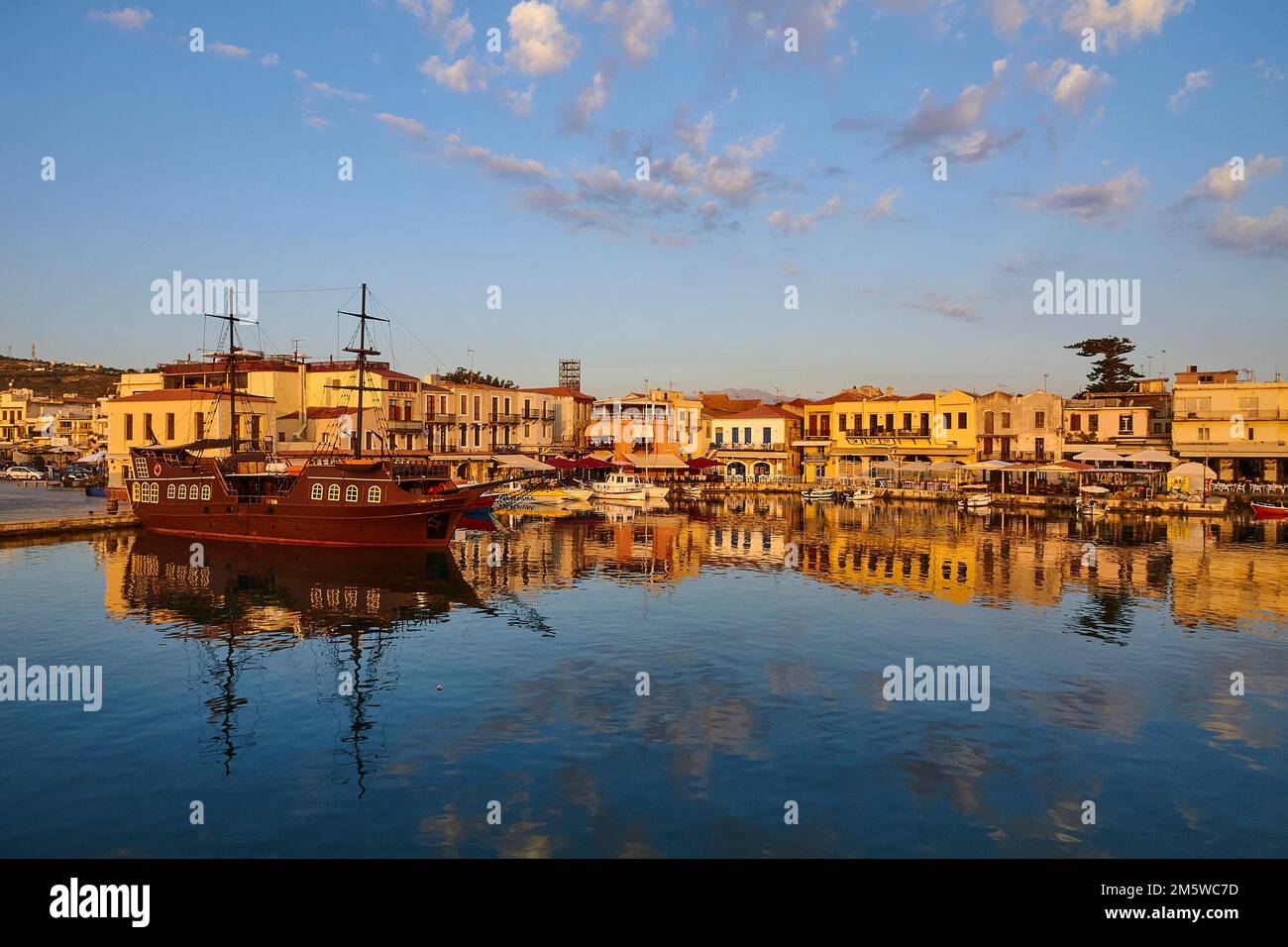 Morning light, sunrise, Venetian harbour, pirate ship, row of houses, colourful houses, reflections in the water, blue sky, few grey-white clouds Stock Photo