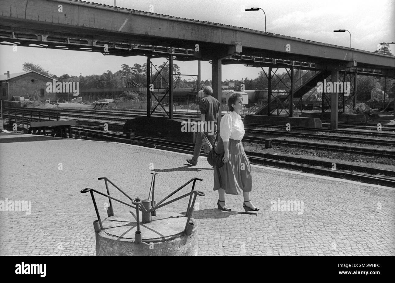 GDR, Berlin, 06. 05. 1990, Strausberg S-Bahn station, platform, woman in blouse and skirt, empty flag holder Stock Photo