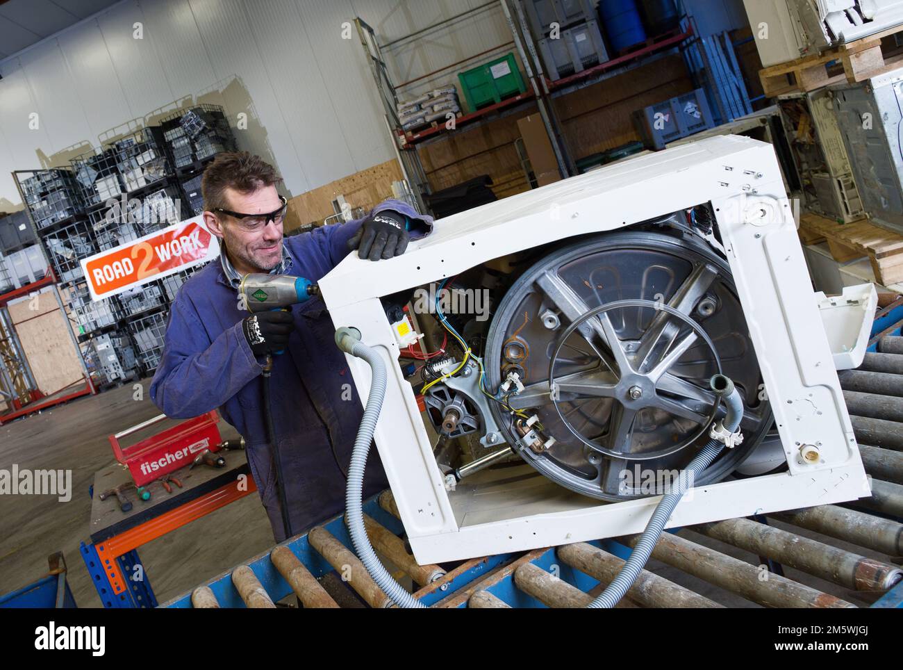 Ewaste. Workplace Road2work, A mechanic disassembles a washing machine