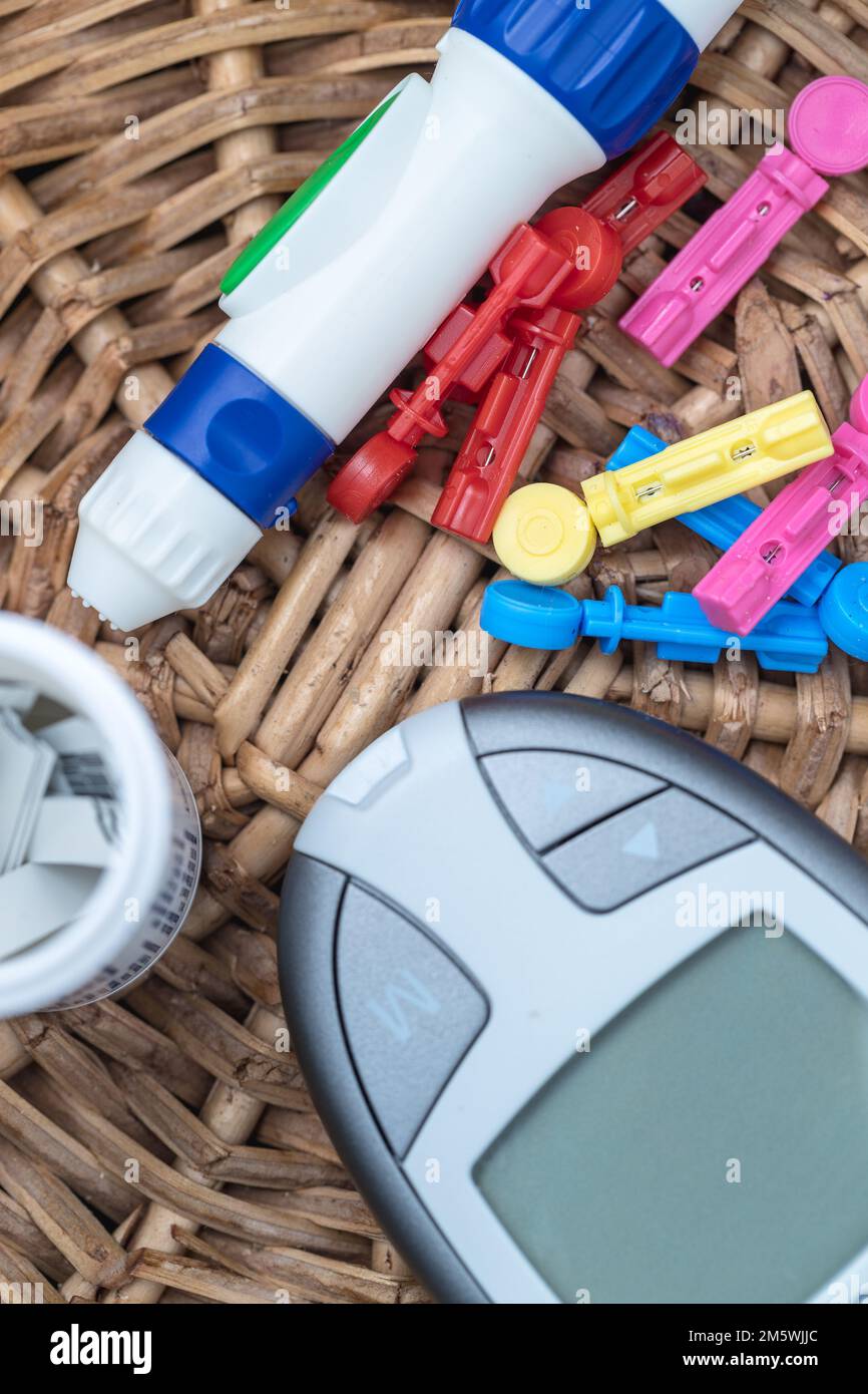 Diabetes testing kit. Glucose meter, lancet, test strips, bandaid on a woven surface. Healthcare concept. Stock Photo