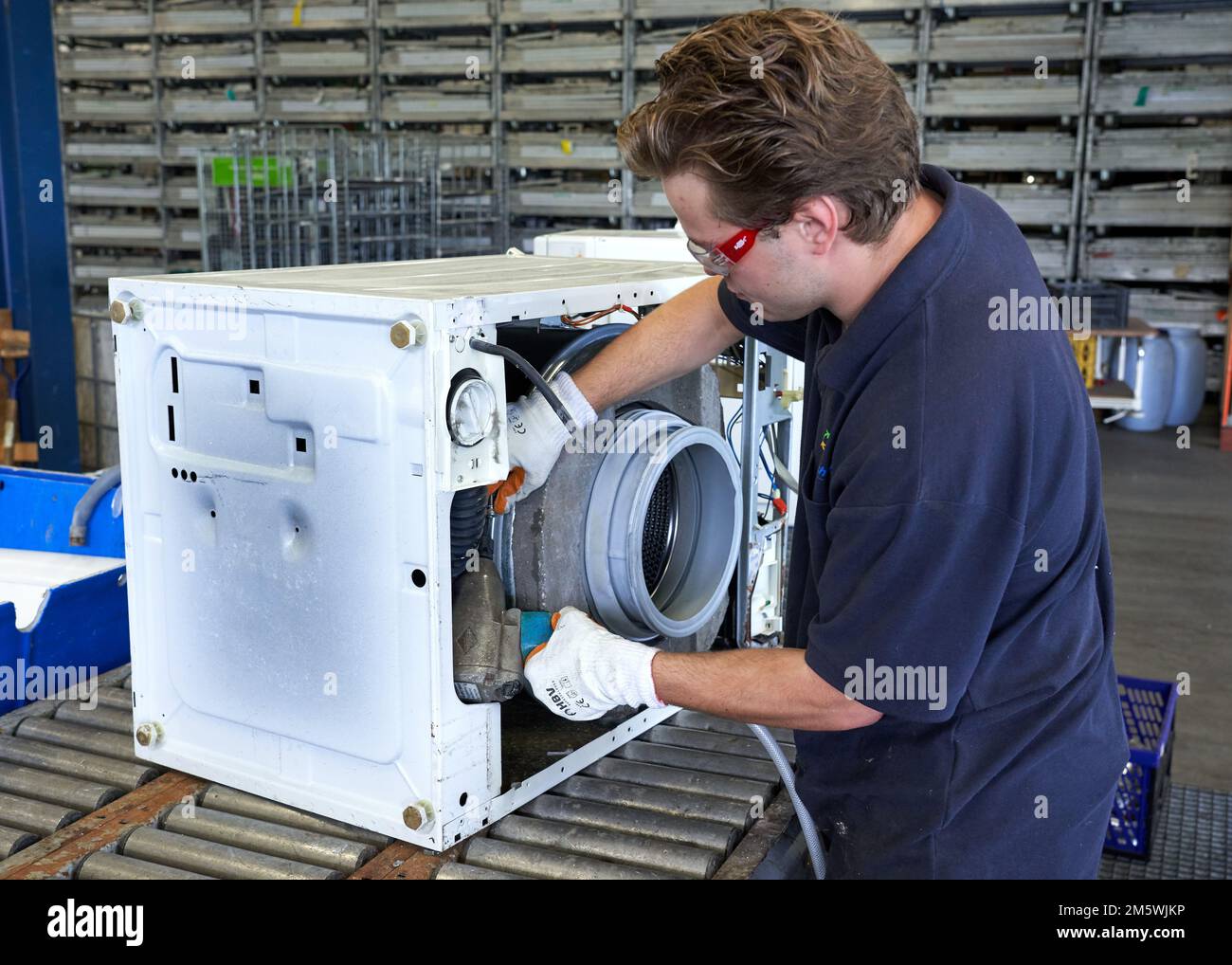 Ewaste. Workplace Road2work, A mechanic disassembles a washing machine