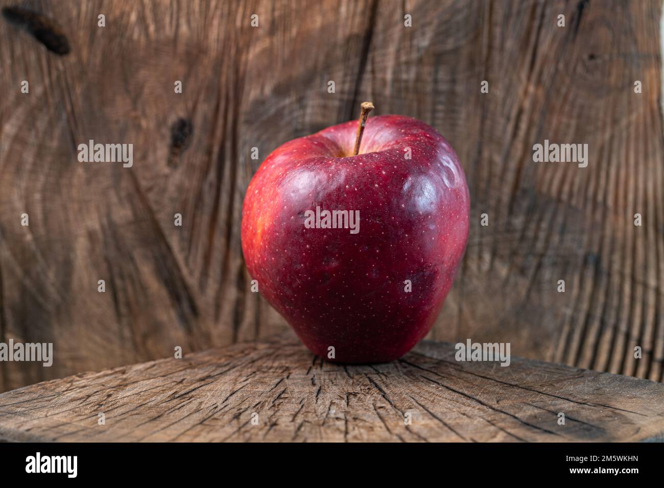 An evocative image of a bright red apple set against a rustic wooden backdrop, capturing the essence of freshness and authentic nature Stock Photo