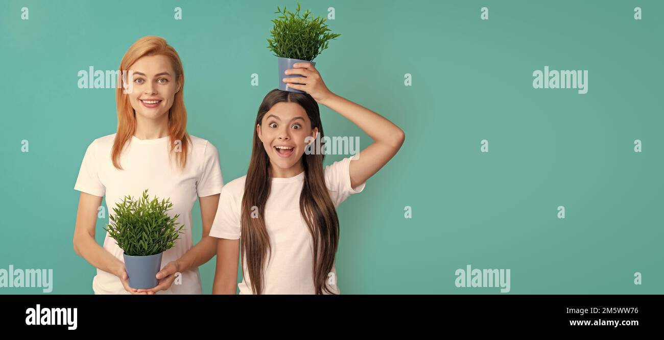 Mother and daughter child banner, copy space, isolated background. Family of mother and surprised girl child holding pot plant on head to grow taller Stock Photo