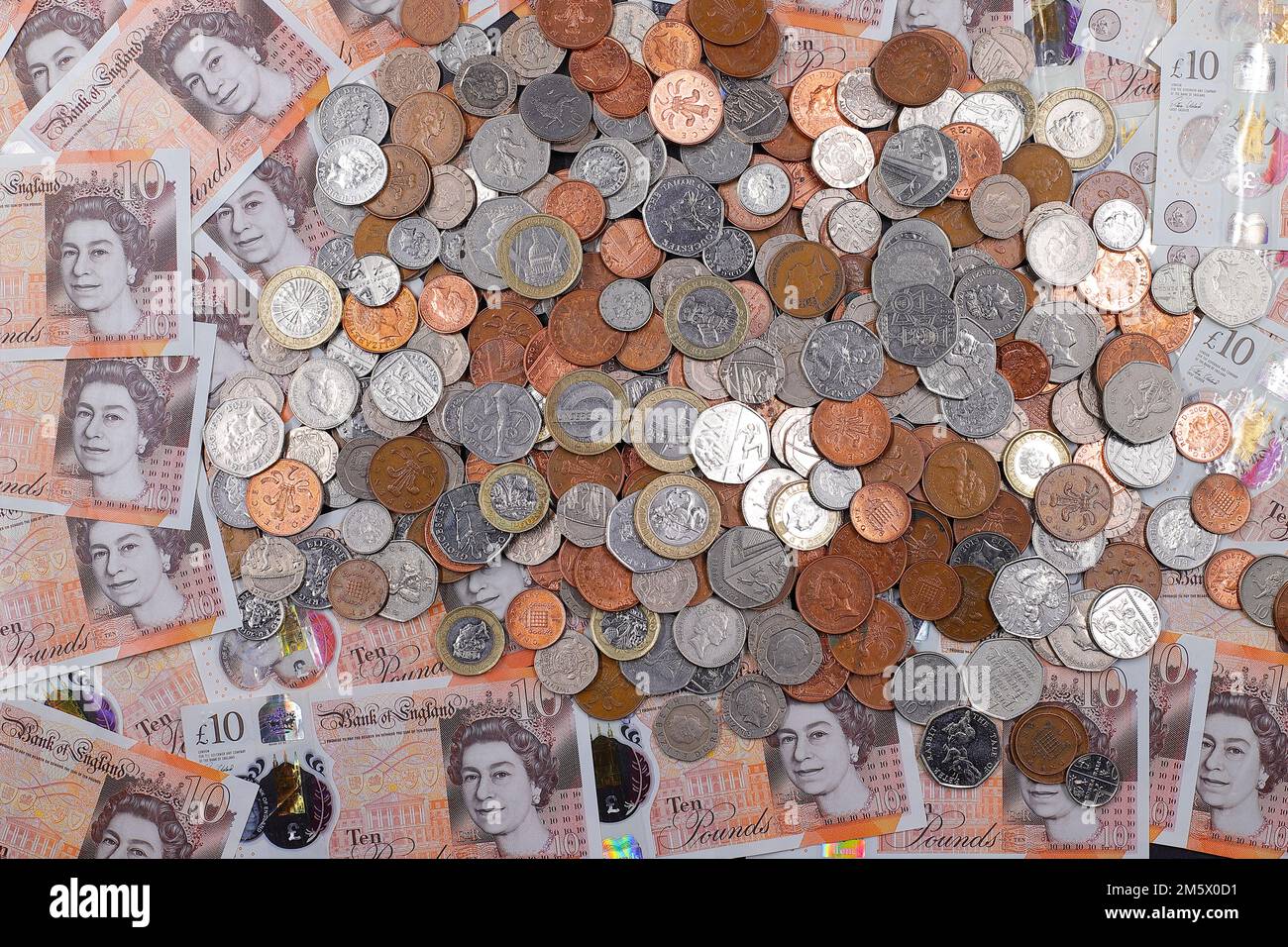£10 bank notes & a pile of British coins including denominations of1p,2p,5p,10p,20p,50p pieces & £1 & £2 coins Stock Photo