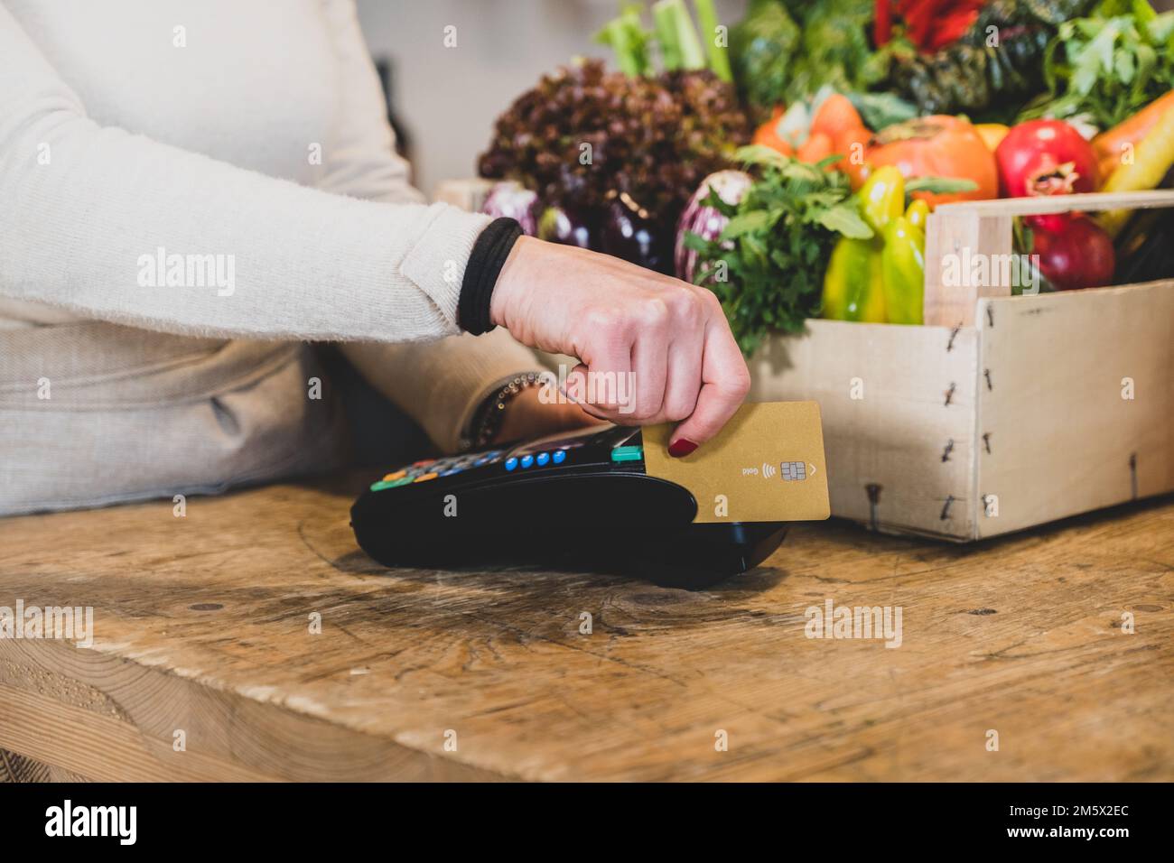 Customer girl paying for shopping at checkout in a grocery store - Young woman taking a credit card from a customer in a biologic market Stock Photo
