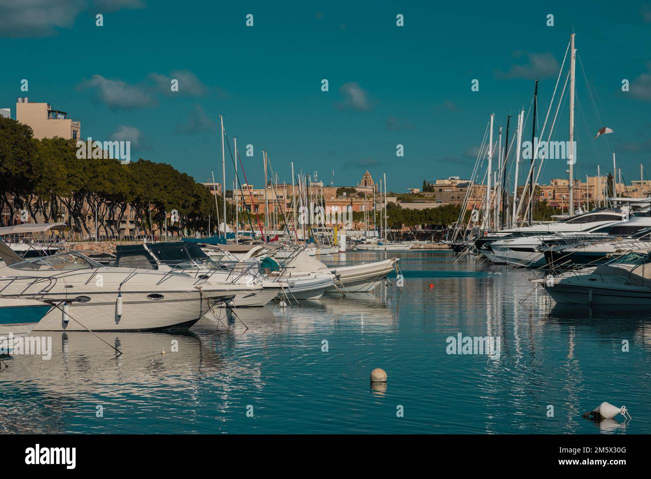Marina in Valletta, Malta on a summer day. Visible multitude of boats and yachts with some buildings in the background. Stock Photo