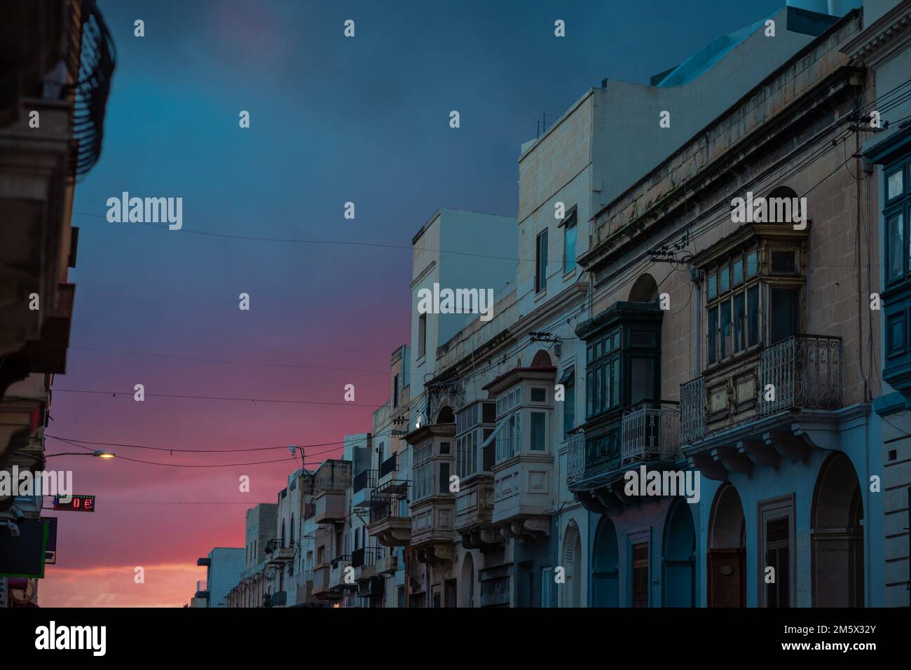 Malta Balcony. Colorful balconies in historical part of Malta close to valetta. Beautiful sky in the background with sun just setting down. Stock Photo