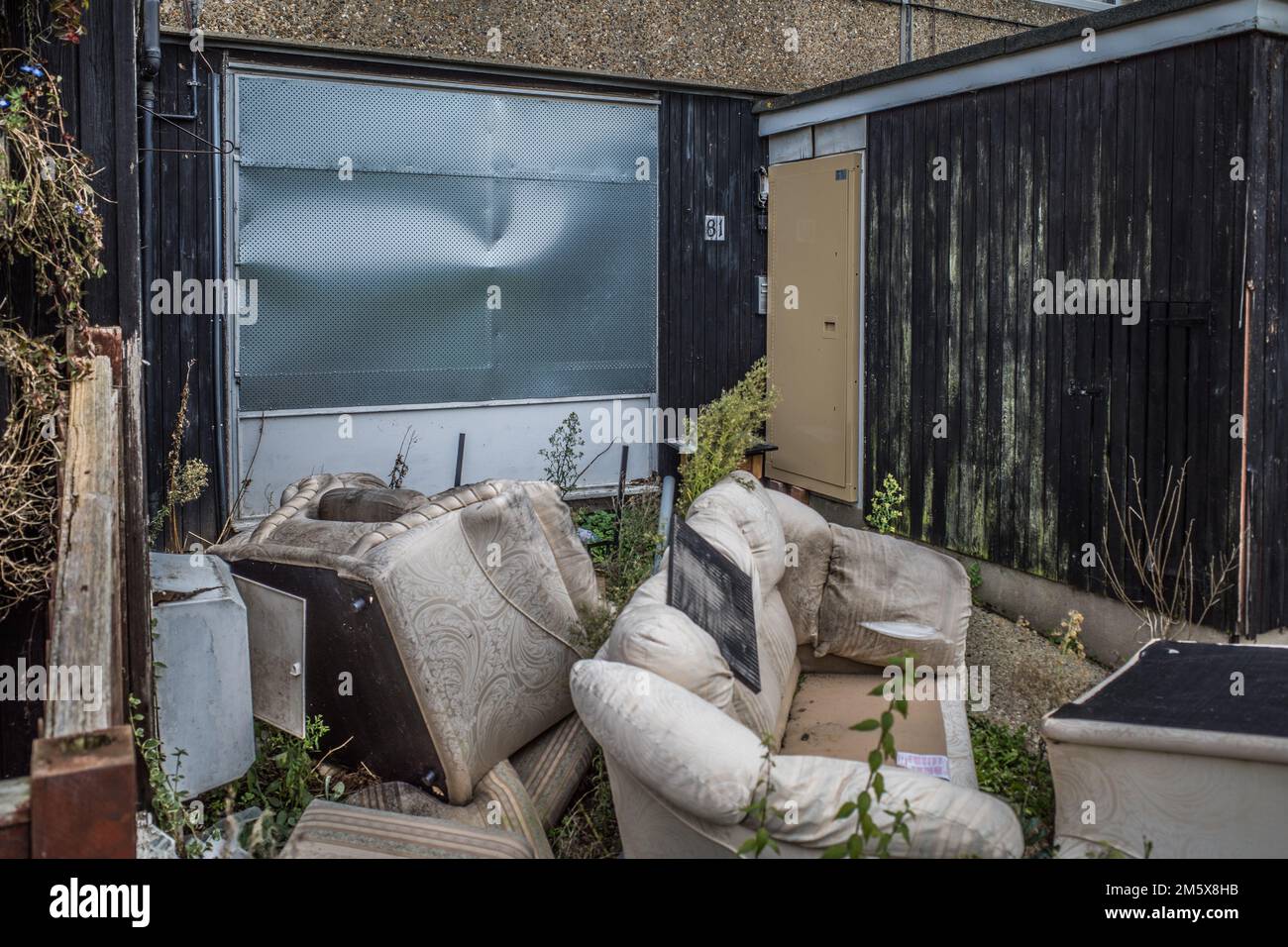 Discarded furniture outside a boarded up abandoned house in a run down housing estate currently being demoted for regeneration, North London, UK. Stock Photo