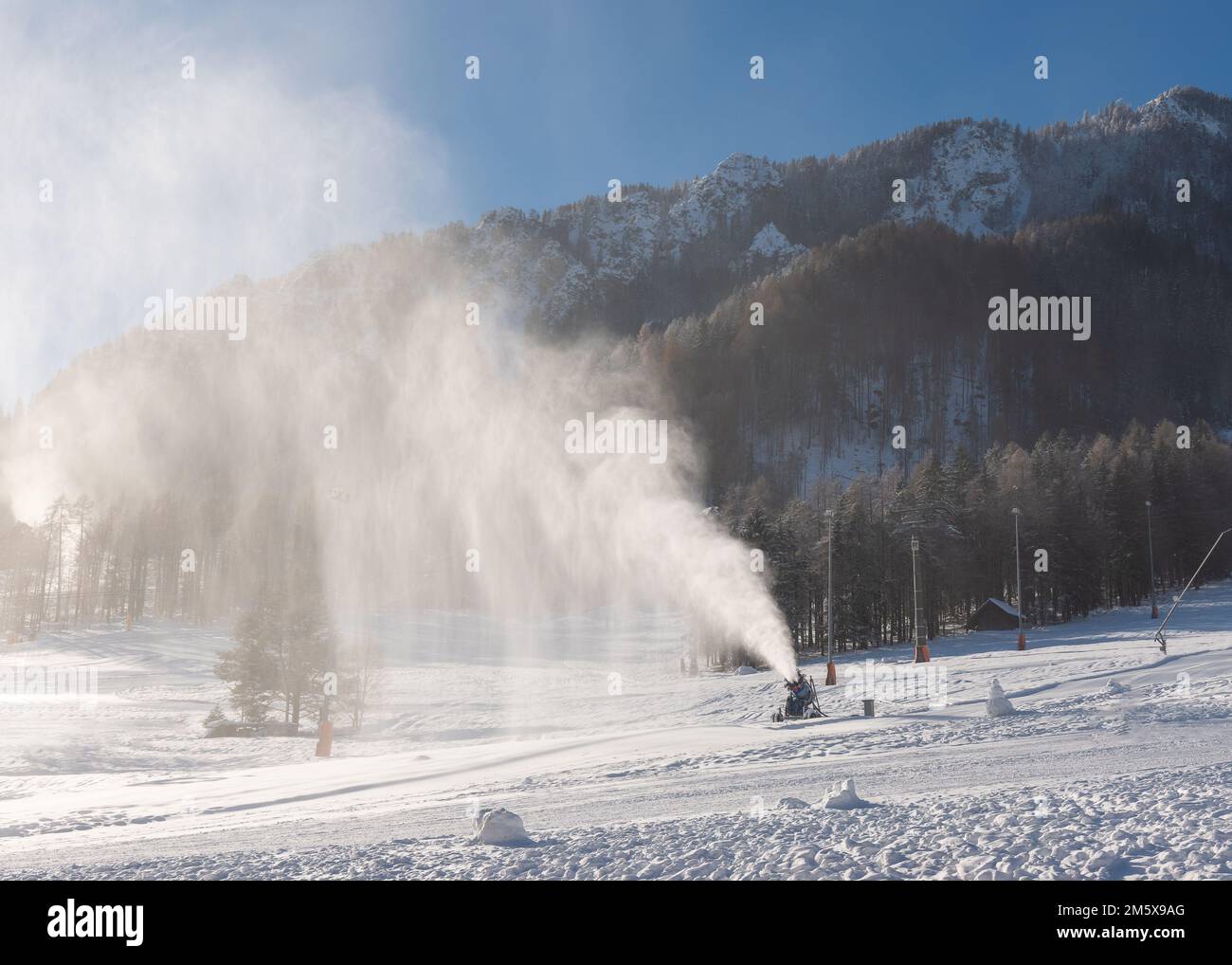 Snowmaking machine snow cannon or gun in action on a cold sunny winter day in ski resort Kranjska Gora, Slovenia Stock Photo