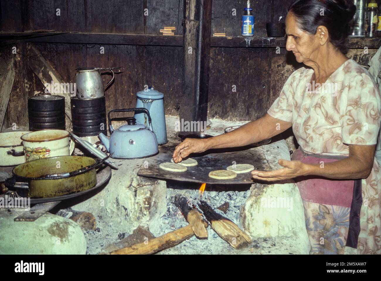 Woman makes corn tortillas by hand and cooks them on a large clay