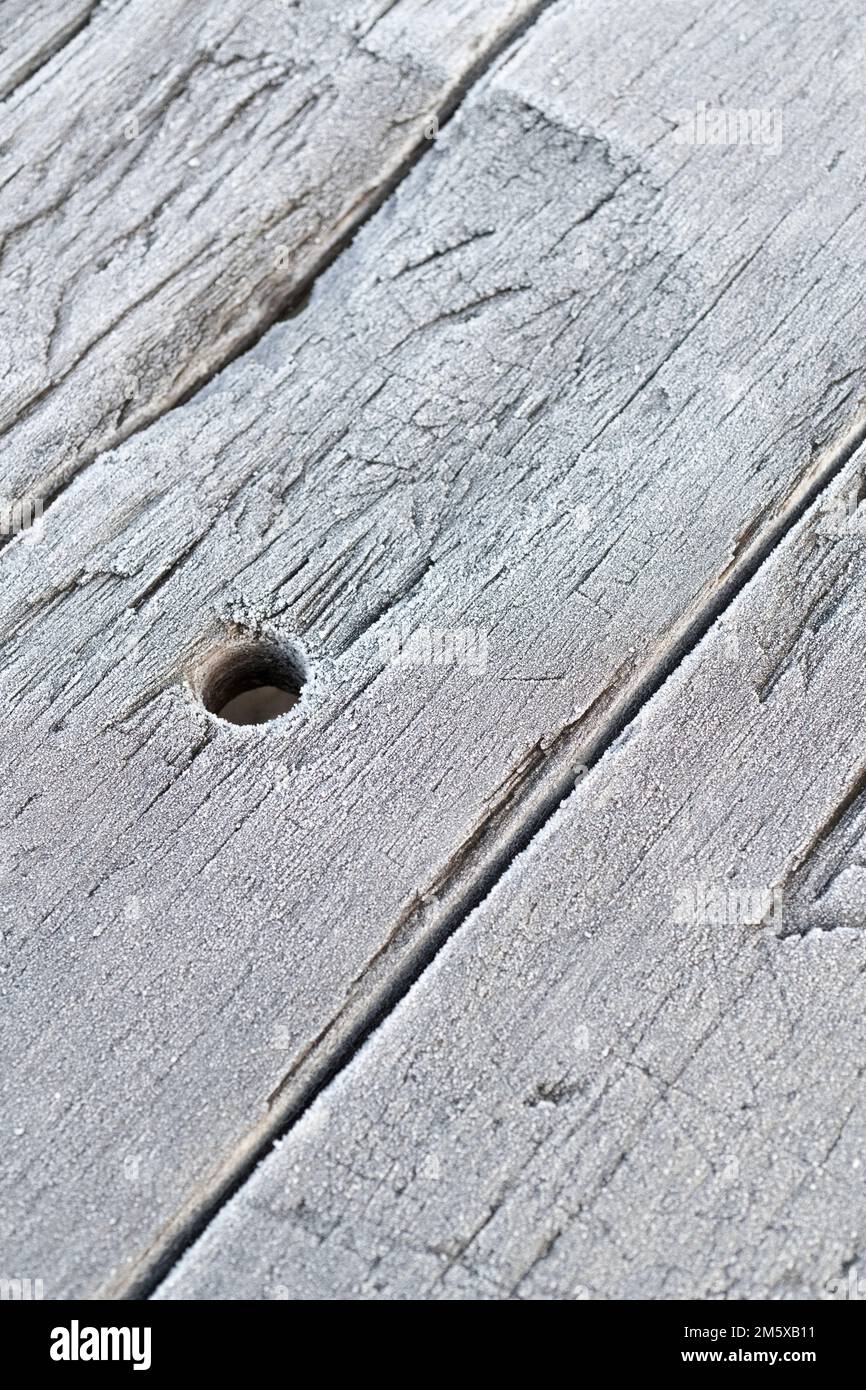 Wooden picnic table planks covered with a fine covering of frost crystals. For UK cold weather snap, frost abstract, or abstract cold weather. Stock Photo