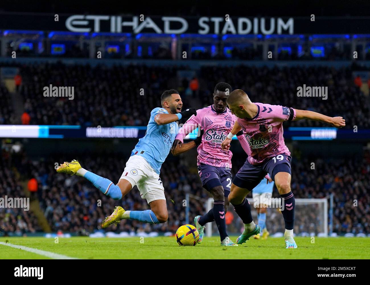 Manchester City's Riyad Mahrez goes down under the challenge from Everton's Vitaliy Mykolenko (right) and Idrissa Gueye during the Premier League match at the Etihad Stadium, Manchester. Picture date: Saturday December 31, 2022. Stock Photo