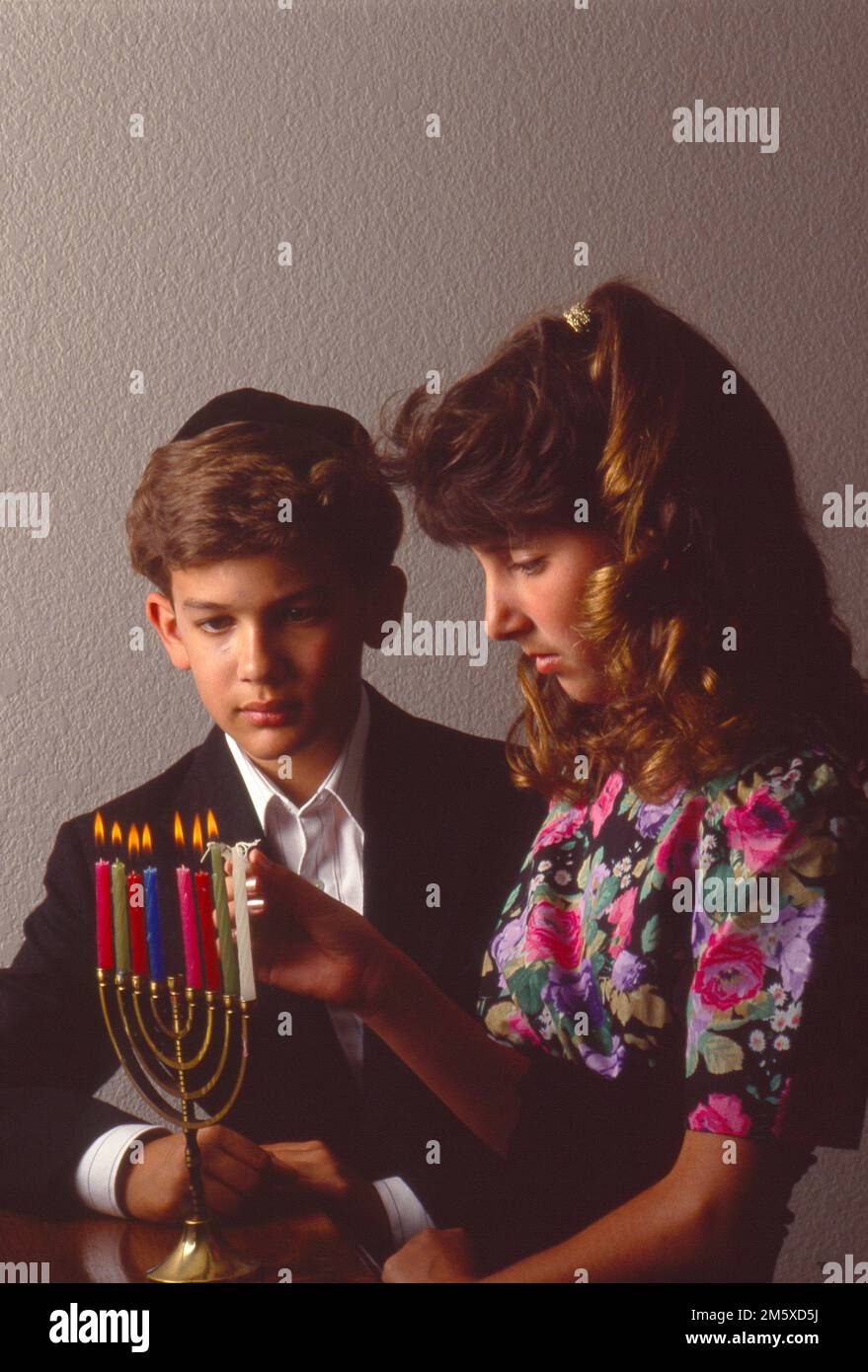 Young boy and a girl lighting a menorah celebrating Hanukkah Stock Photo