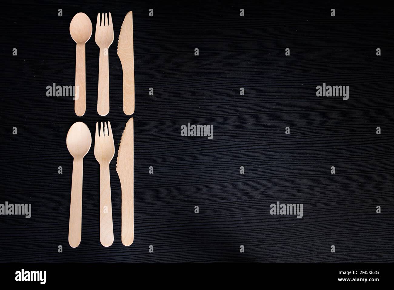 disposable eco-friendly wooden spoons, forks and knives on a dark background Stock Photo