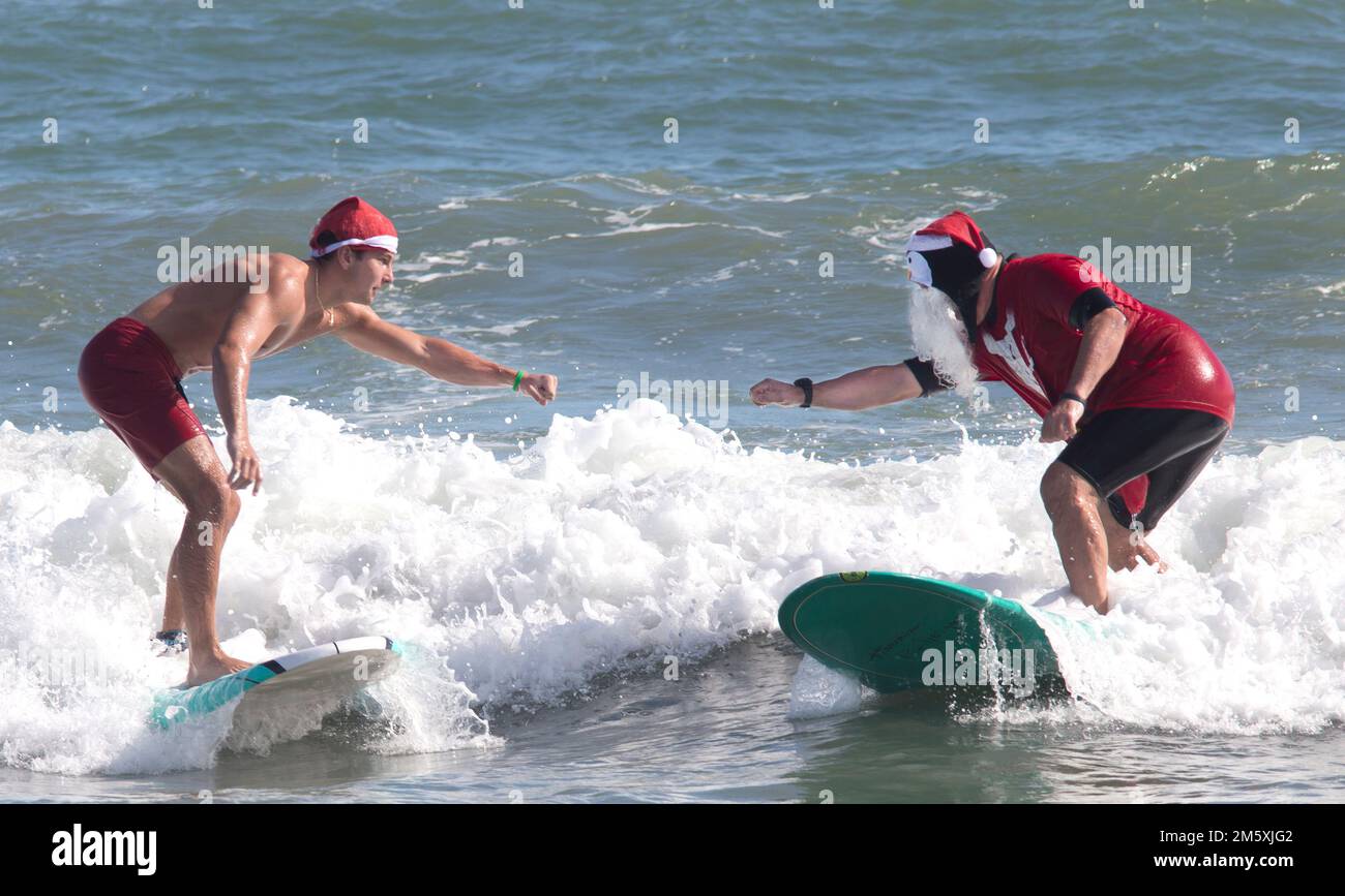 Cocoa Beach, Florida, USA December 24th, 2021 Two surfers attempt a fist bump at the annual
