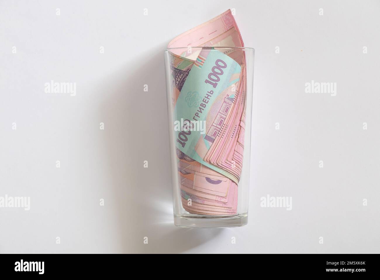 hryvnia and dollar lie in a glass cup on a white background Stock Photo