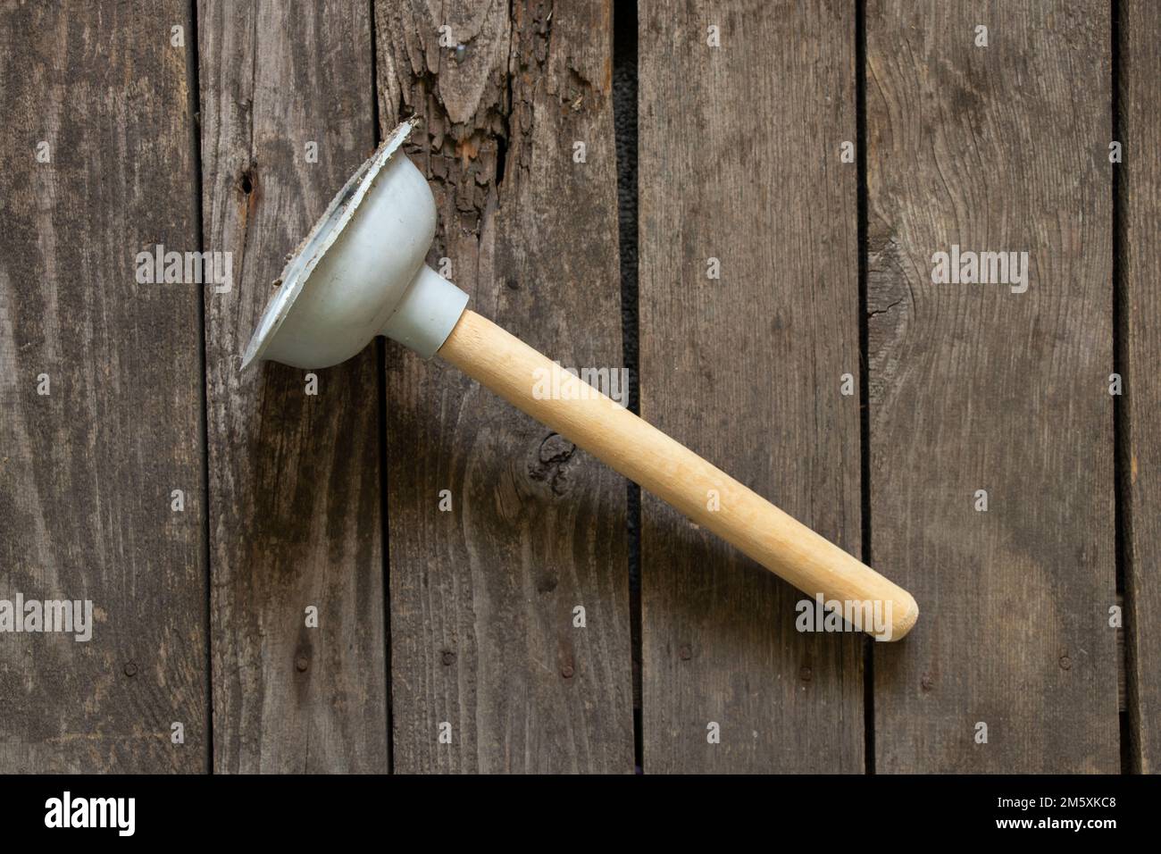 Toilet rubber plug with wooden handle for pipe cleaning on wooden background Stock Photo