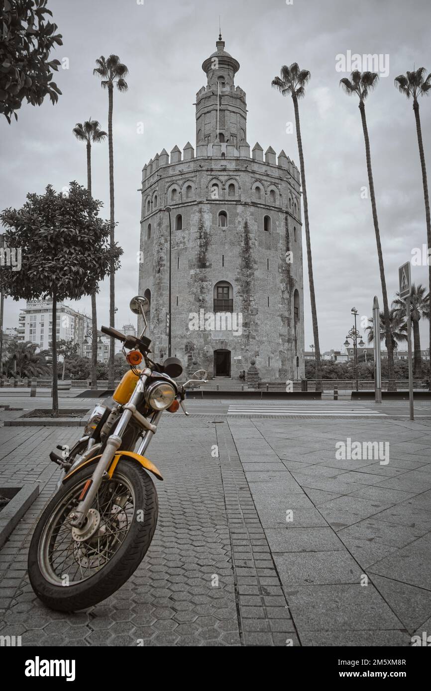 Random Motorcycle in front of Torre del Oro in black and white. Only the motorcycle is in color Stock Photo