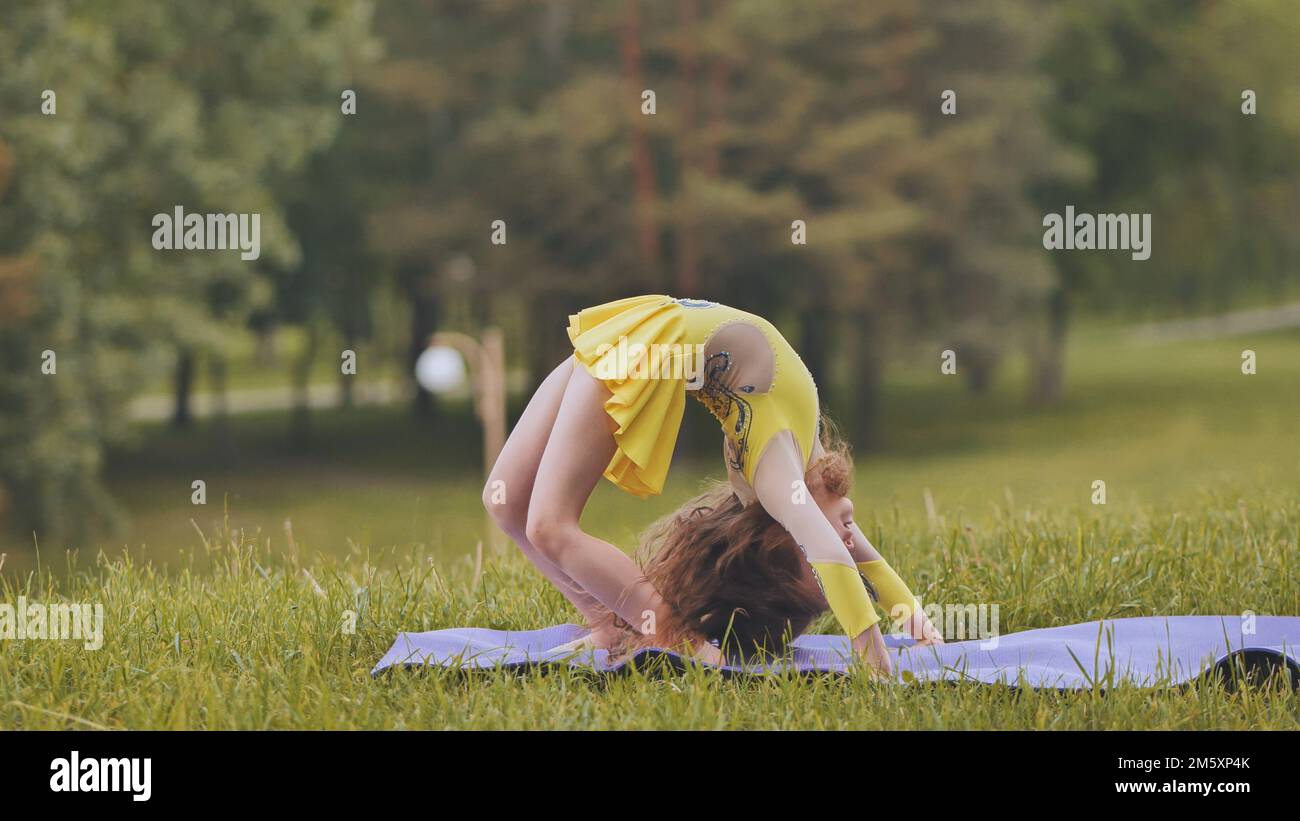 A little girl performs the elements of rhythmic gymnastics in the park