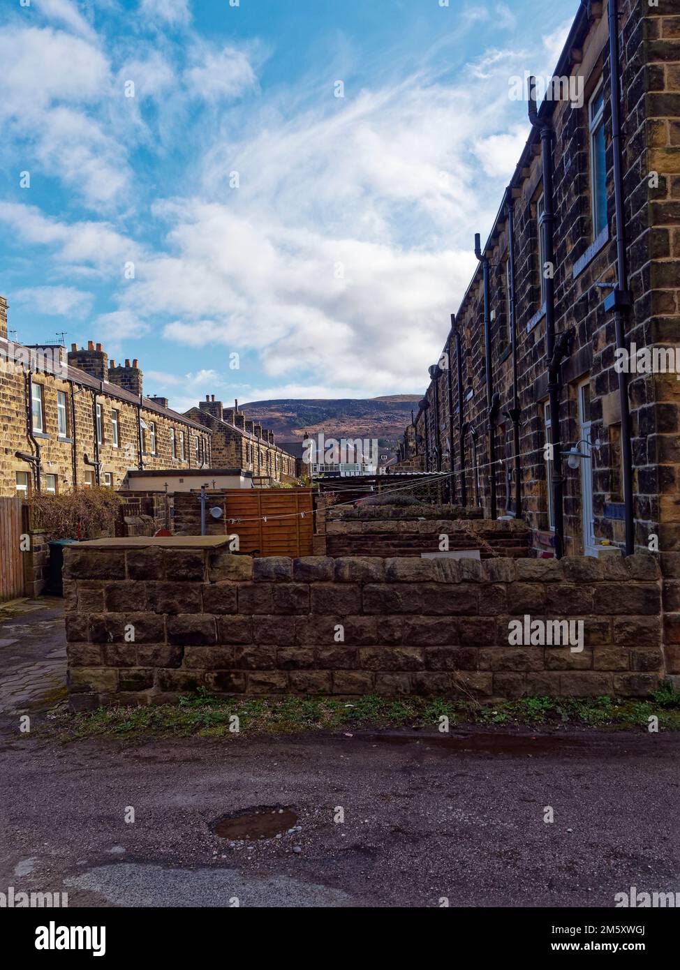 Back gardens of stone built terraced houses in likely Town in west Yorkshire with Ilkley Moor in the Background under a blue sky. Stock Photo