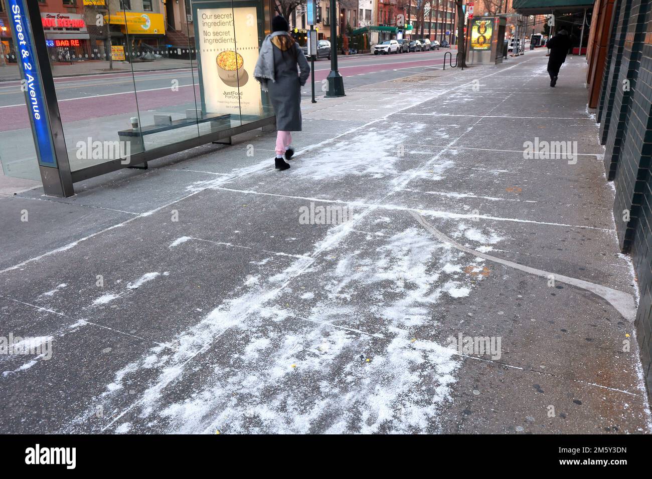 Deicing salt on a sidewalk in New York City. rock salt on a sidewalk in anticipation of icy winter weather. Stock Photo