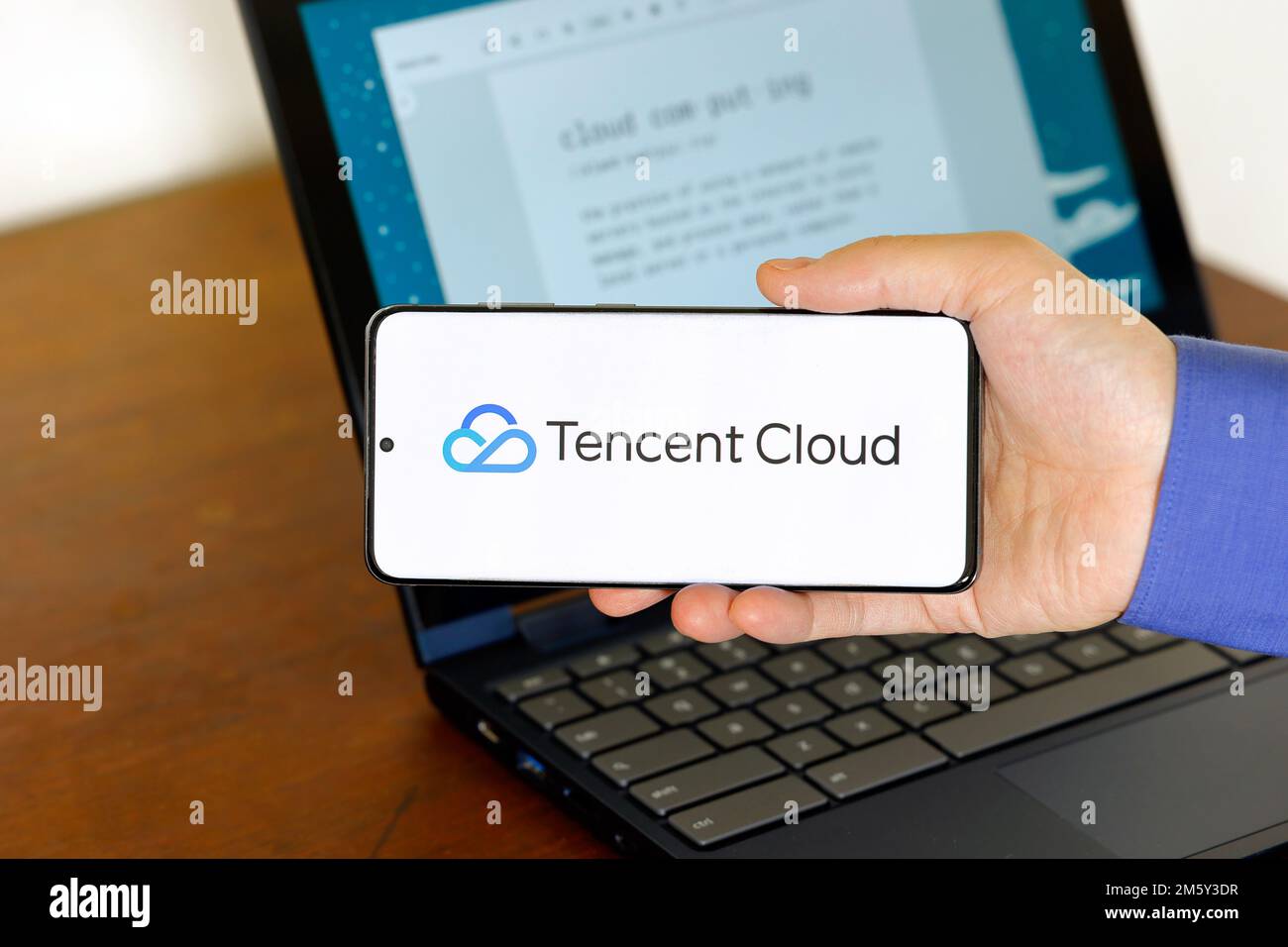 Logo of Tencent Cloud on a smartphone in front of a computer. Tencent Cloud is a cloud computing technology company, a subsidary of Tencent Holdings. Stock Photo