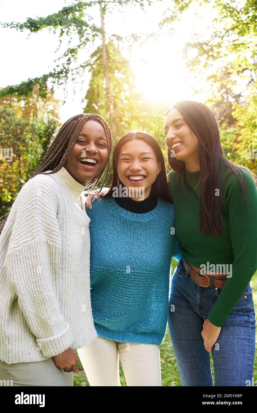 Vertical Portrait of three girls outside looking at camera. Friends multi-ethnic groups of people Stock Photo