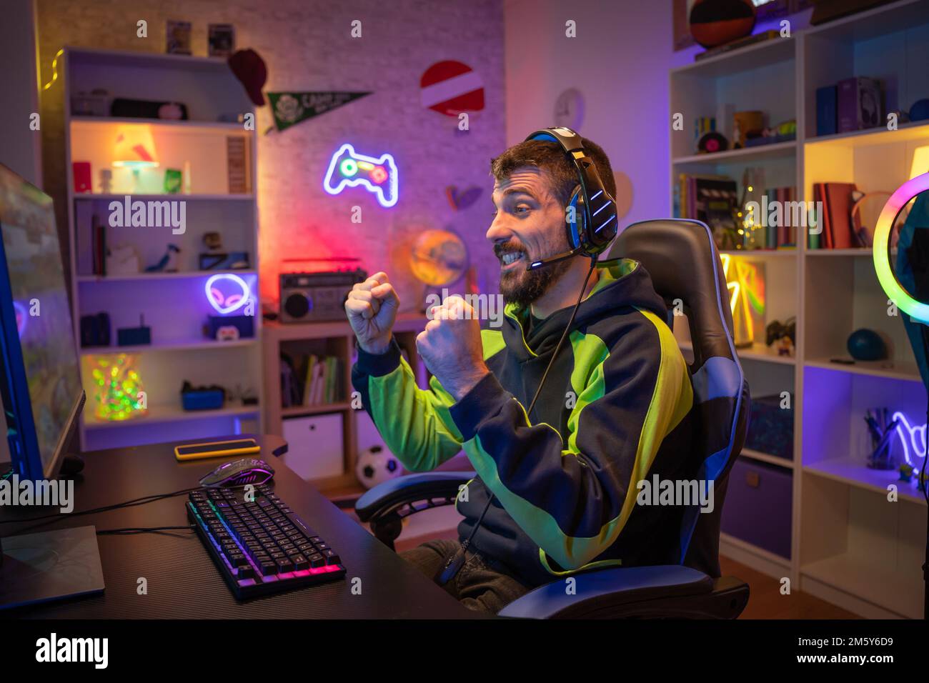 Professional Gamer winning and celebrating victory Online Video Game on Computer side view Stock Photo