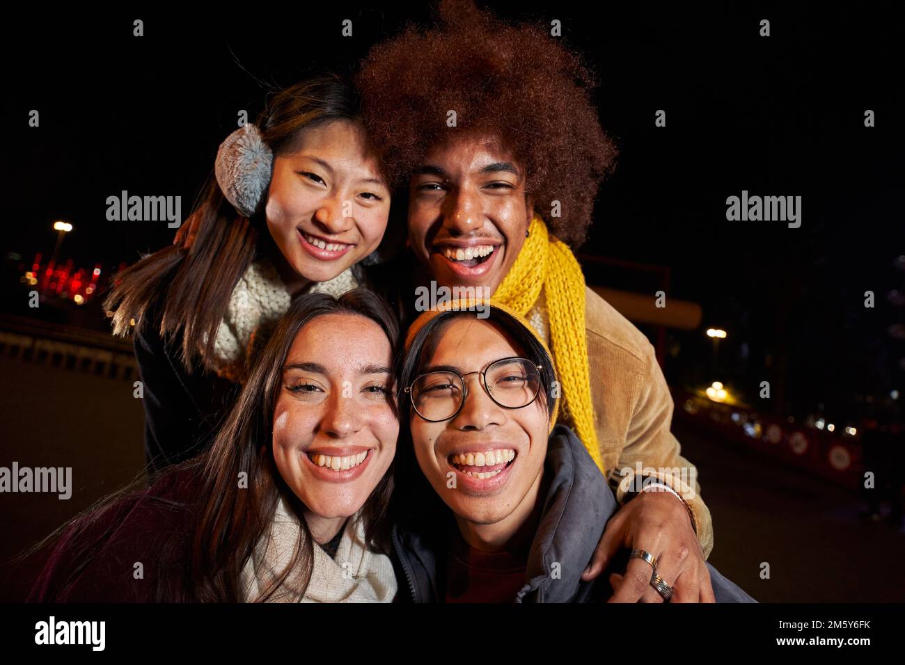 Selfie of a group of happy people taking selfie photo in the night with a phone in winter clothes. Stock Photo