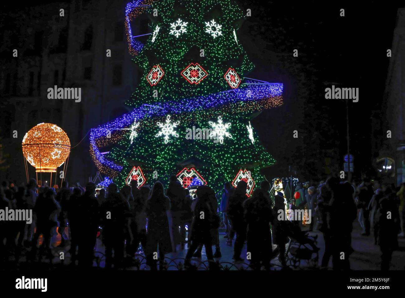 People seen walking near the Christmas tree on Deribasovskaya Street. In Odessa, a New Year's tree was installed on Deribasivska Street. The mayor's office decided to place the main symbol of the New Year despite the war and blackouts, calling it the 'Christmas tree of indomitability.' Stock Photo