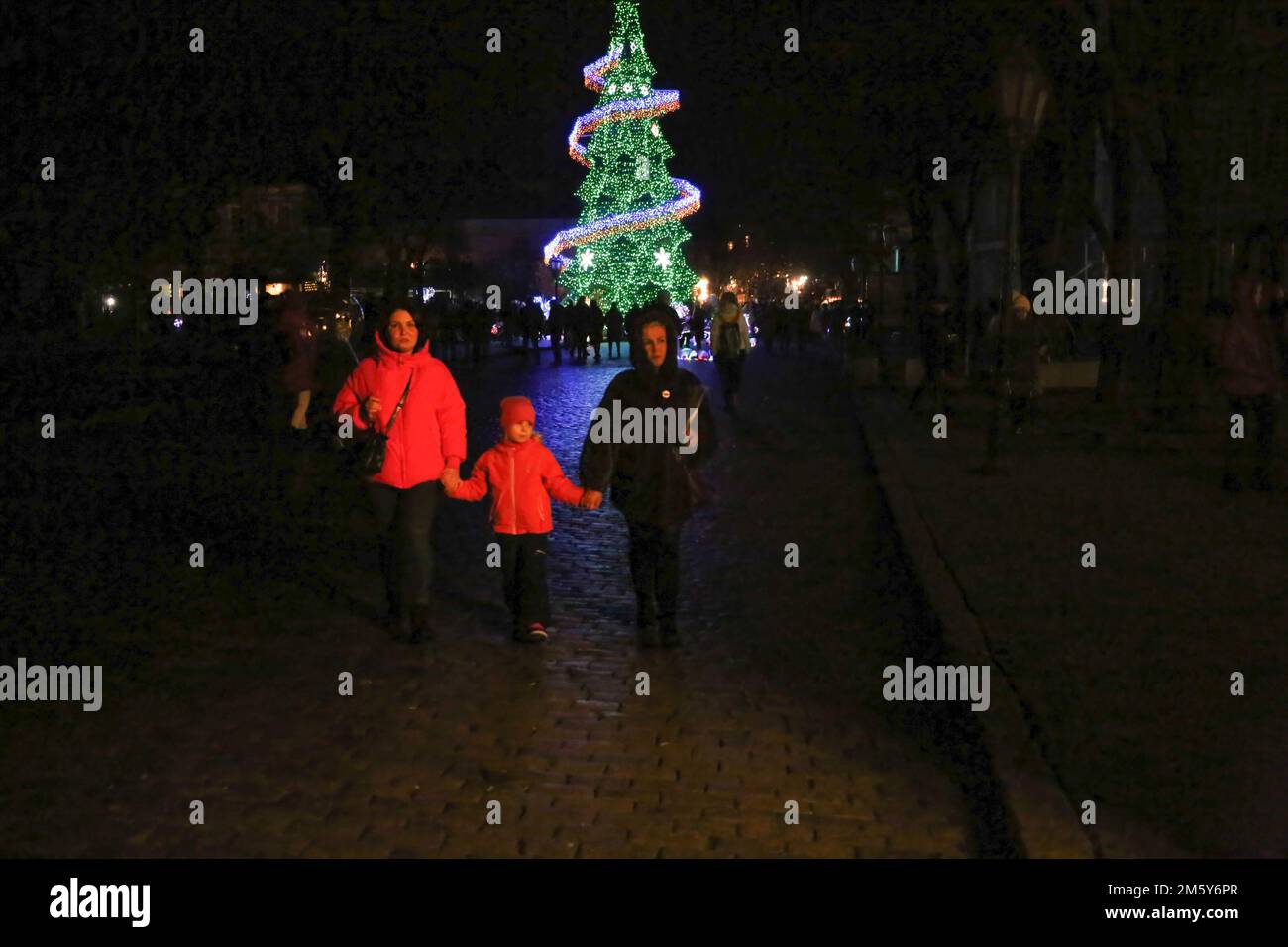 Odessa, Ukraine. 31st Dec, 2022. People seen walking near the Christmas tree on Deribasovskaya Street. In Odessa, a New Year's tree was installed on Deribasivska Street. The mayor's office decided to place the main symbol of the New Year despite the war and blackouts, calling it the 'Christmas tree of indomitability.' (Photo by Viacheslav Onyshchenko/SOPA Im/Sipa USA) Credit: Sipa USA/Alamy Live News Stock Photo