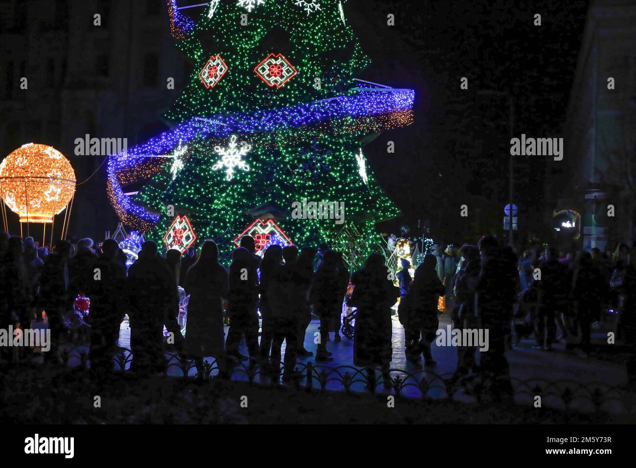 Odessa, Ukraine. 31st Dec, 2022. People seen walking near the Christmas tree on Deribasovskaya Street. In Odessa, a New Year's tree was installed on Deribasivska Street. The mayor's office decided to place the main symbol of the New Year despite the war and blackouts, calling it the ''Christmas tree of indomitability. (Credit Image: © Viacheslav Onyshchenko/SOPA Images via ZUMA Press Wire) Stock Photo