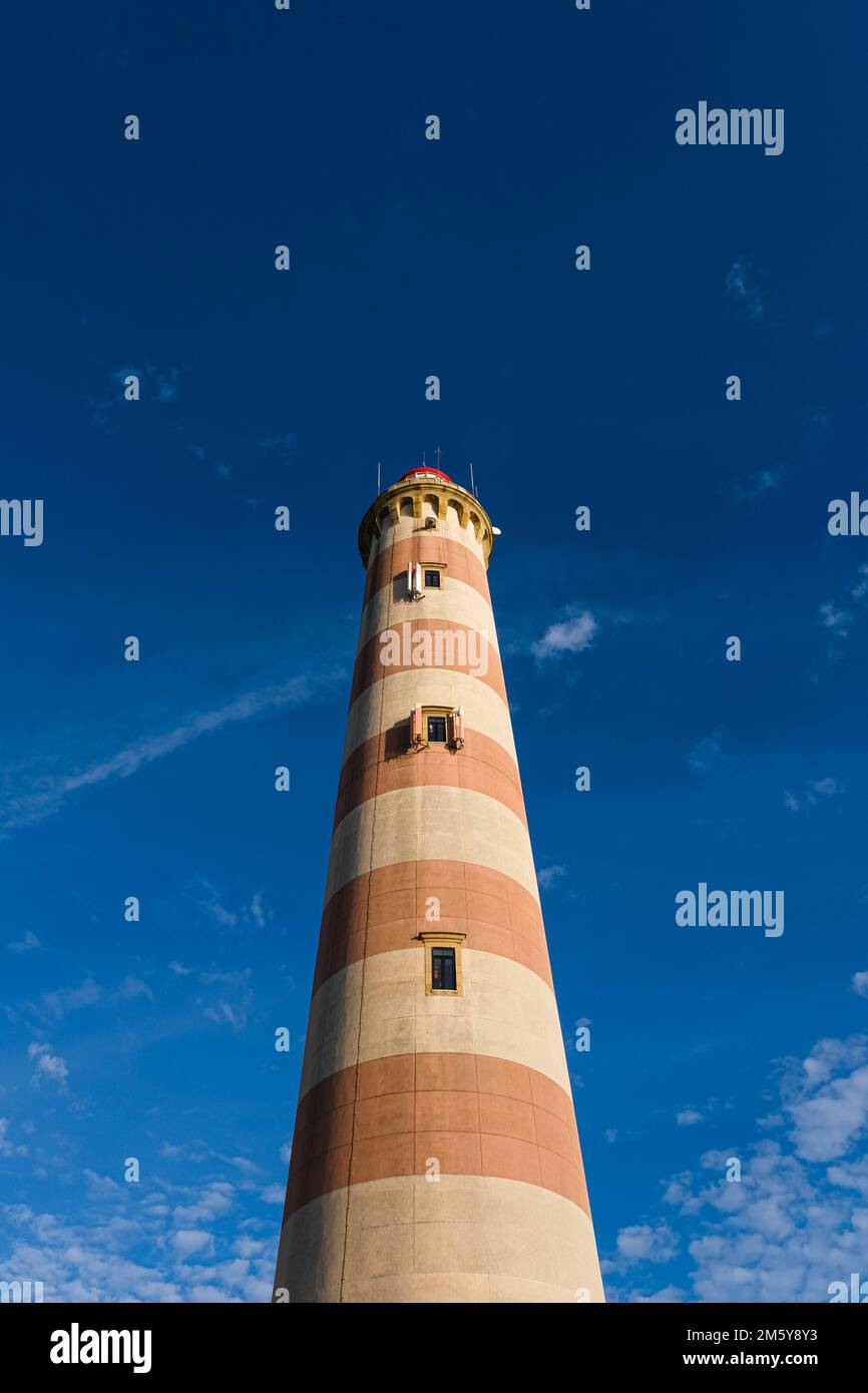 View of the old striped lighthouse and bright blue sky. The main