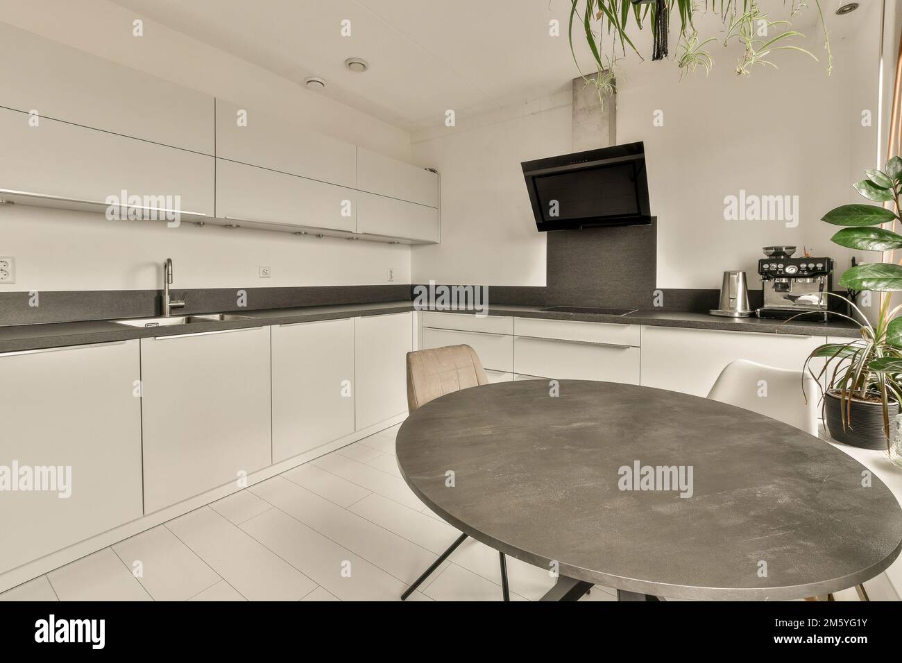 a small kitchen with white cabinets and black counter tops on the counters in this photo is taken from the inside Stock Photo