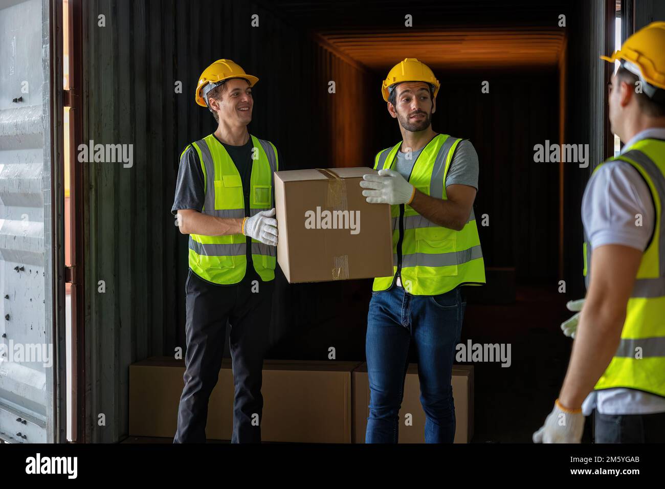 Worker carry carton box taken from 40 feet steel container on the trailer truck park at warehouse Stock Photo