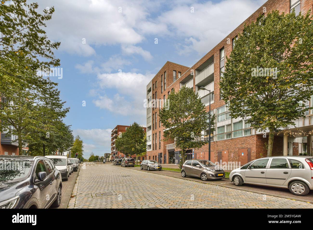 a city street with cars parked on the side and buildings in the back ...