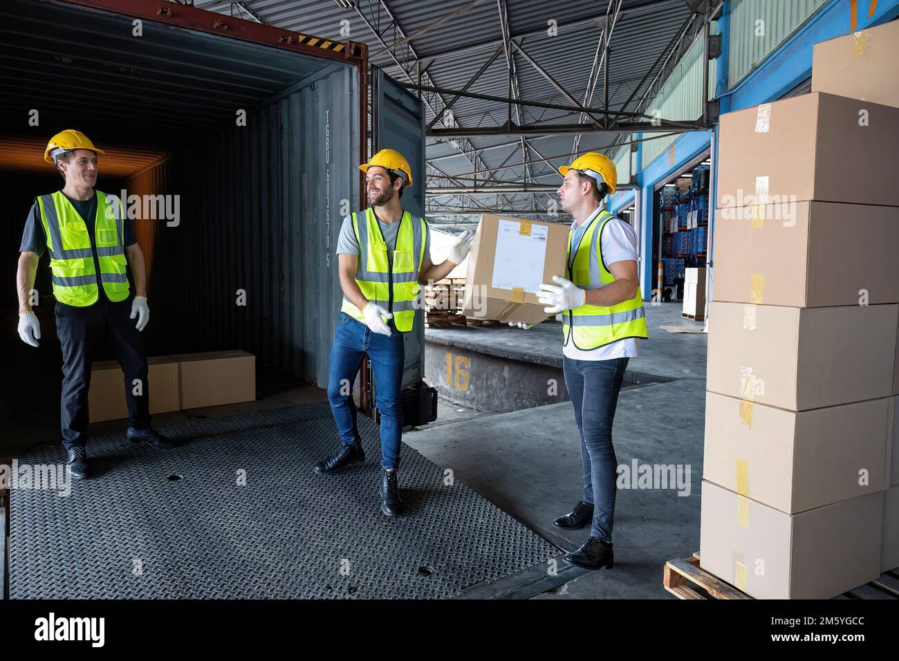 Worker carry carton box taken from 40 feet steel container on the trailer truck park at warehouse Stock Photo