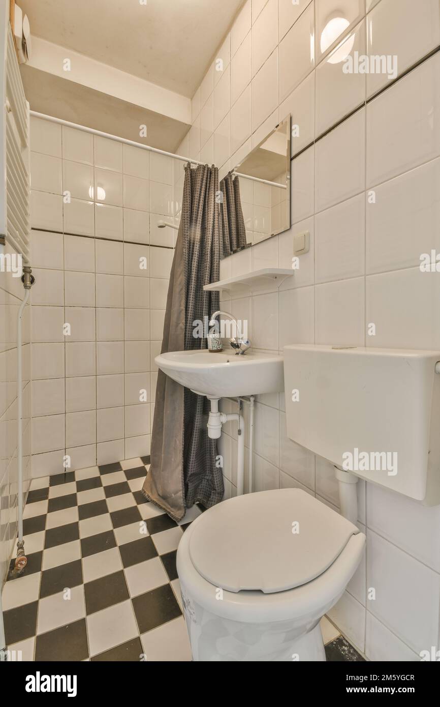 a bathroom with black and white checkered tiles on the floor, sink, toilet, and shower in it Stock Photo