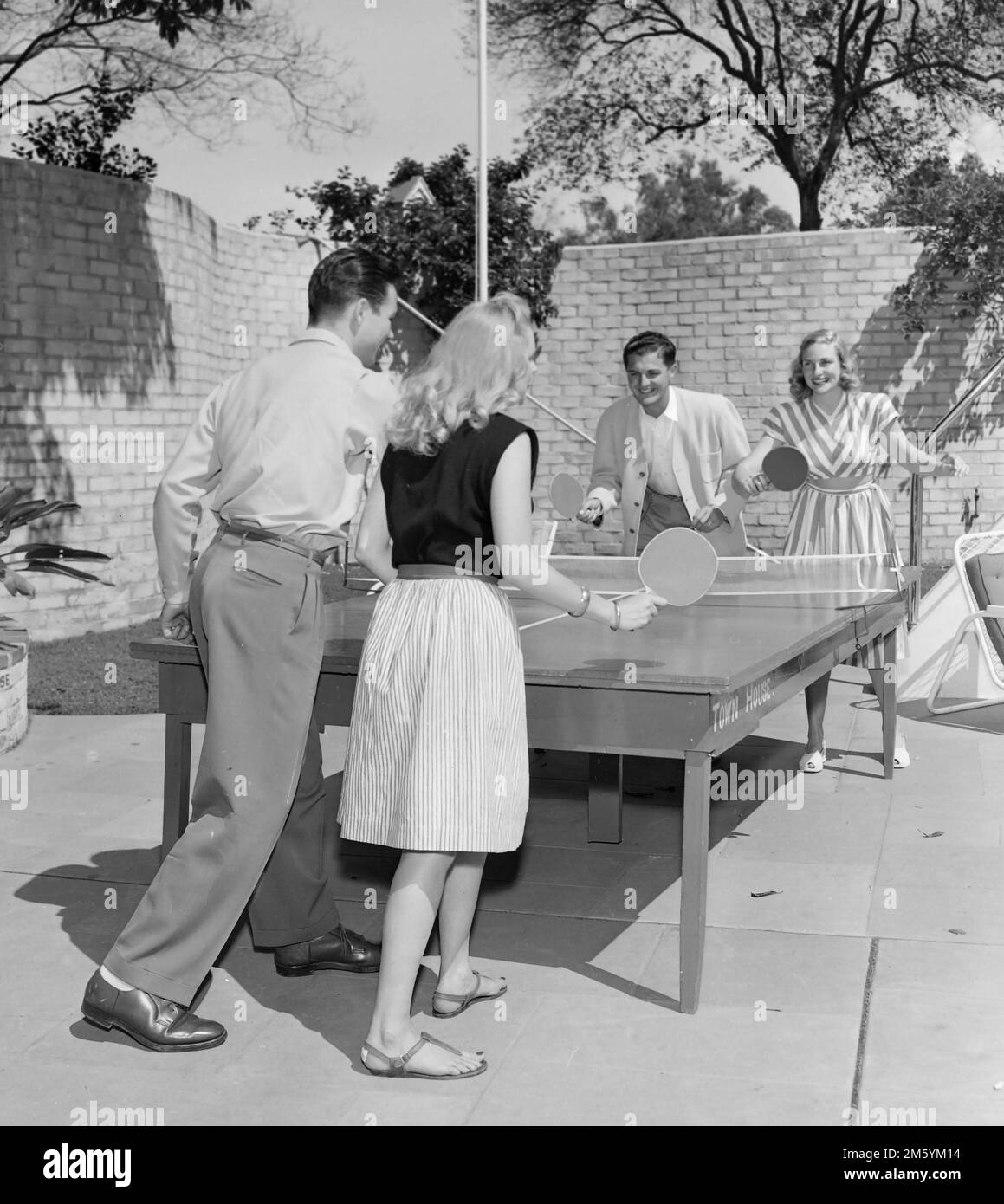 Young people play doubles ping pong or table tennis in Southern California, ca. 1960. Stock Photo