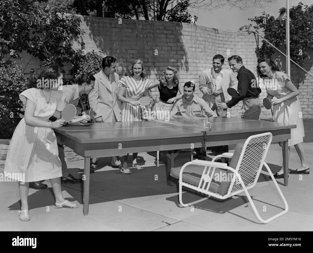 A crowd of young people play ping pong or table tennis in Southern