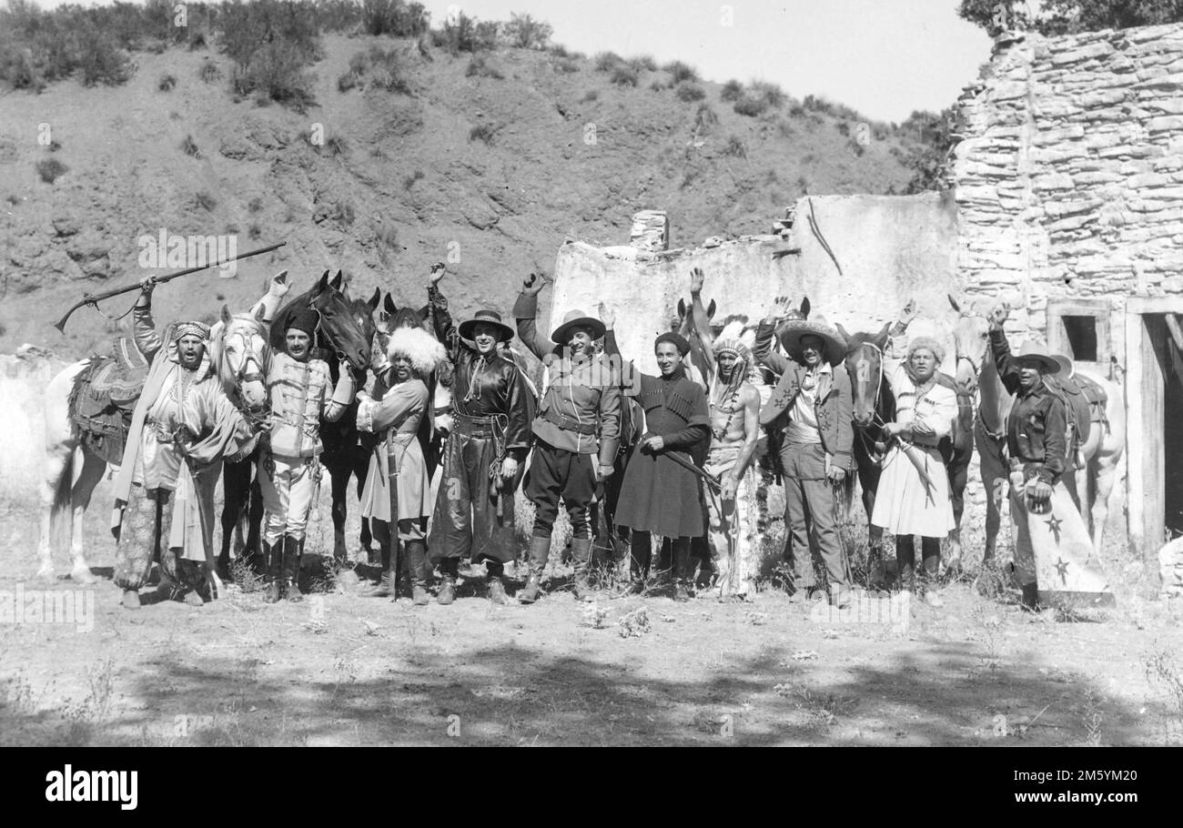 A group of actors dress as cowboys, Indians and others wave and cheer on what is possibly a movie set for a photo, c. 1940s. Stock Photo