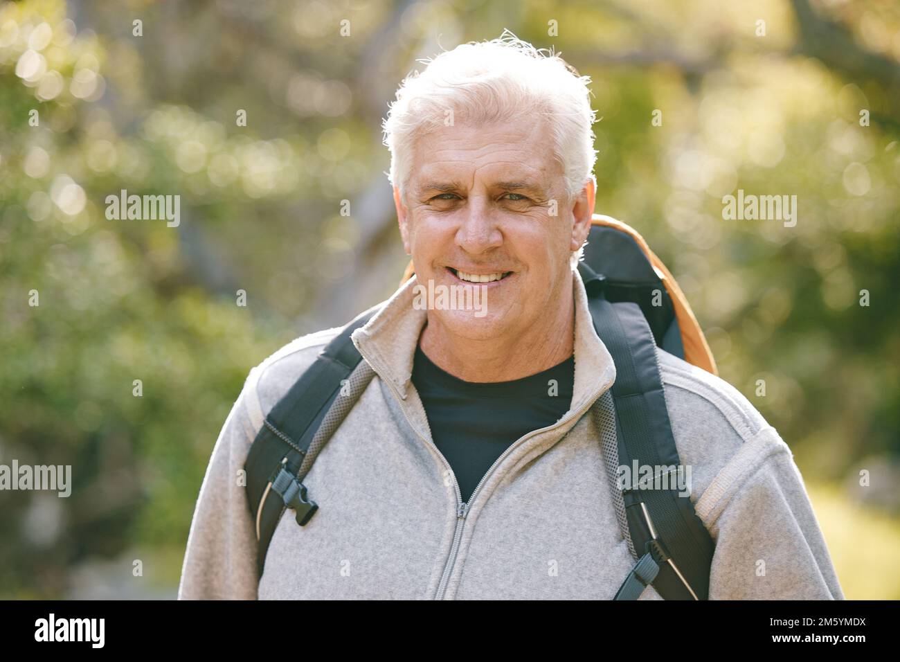 Hiking, fitness and elderly man in nature for exercise and trekking in the park, vitality and active lifestyle portrait. Senior hiker, travel and Stock Photo